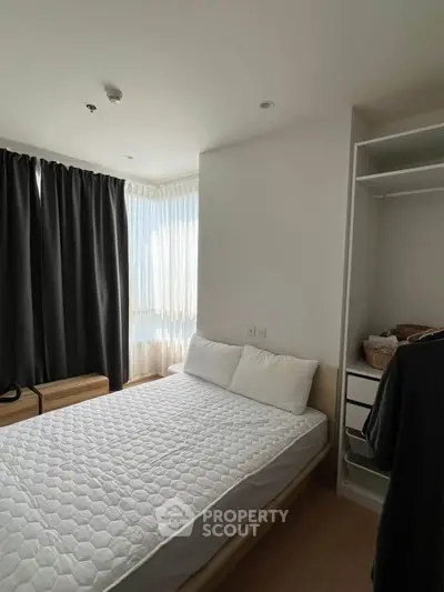 Cozy bedroom with natural light, featuring a comfortable bed and ample storage space.