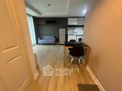 Modern open-plan living room with kitchen, featuring sleek furniture and wooden flooring.