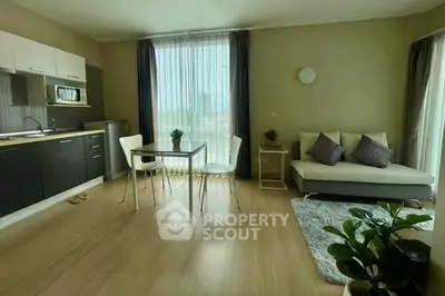 Modern open-layout living room with kitchen, featuring sleek furniture and natural light.