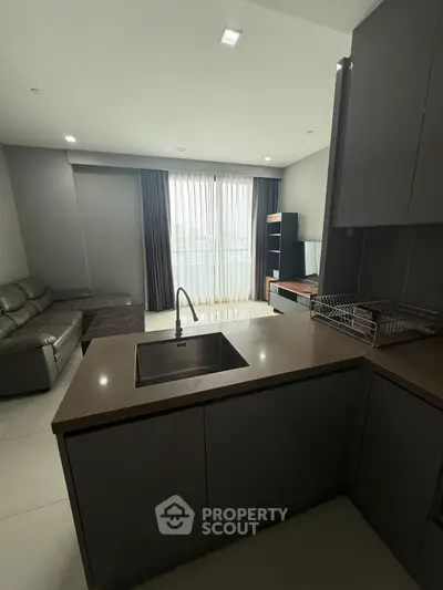Modern open-layout living room with sleek kitchen island and large window view.