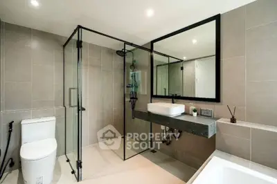 Modern bathroom with glass shower, sleek fixtures, and neutral tiles.