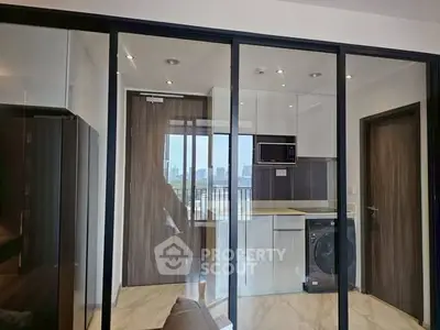 Modern kitchen with glass partition, sleek cabinetry, and city view.
