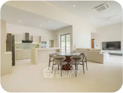 Spacious open-plan living room with modern kitchen and dining area, featuring sleek furniture and ample natural light.