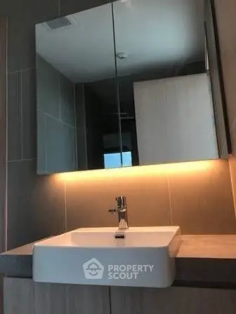 Modern bathroom with sleek sink and illuminated mirror in stylish apartment.