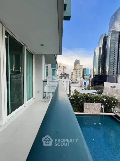 Modern balcony with city view overlooking pool in urban high-rise building.