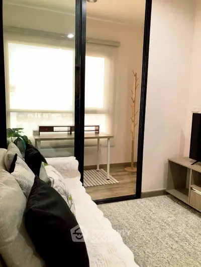 Cozy living room with modern decor and sliding glass doors leading to a bright study area.