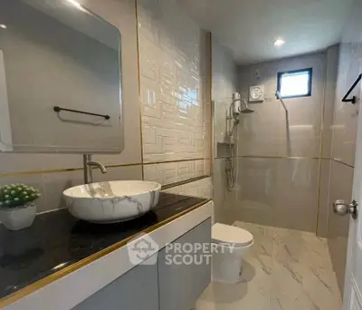 Modern bathroom with sleek design, featuring a stylish sink, elegant tiles, and a spacious shower area.