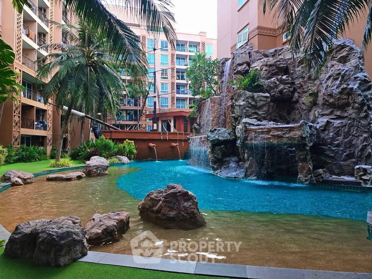 Luxurious condo with stunning pool and waterfall feature in tropical setting.