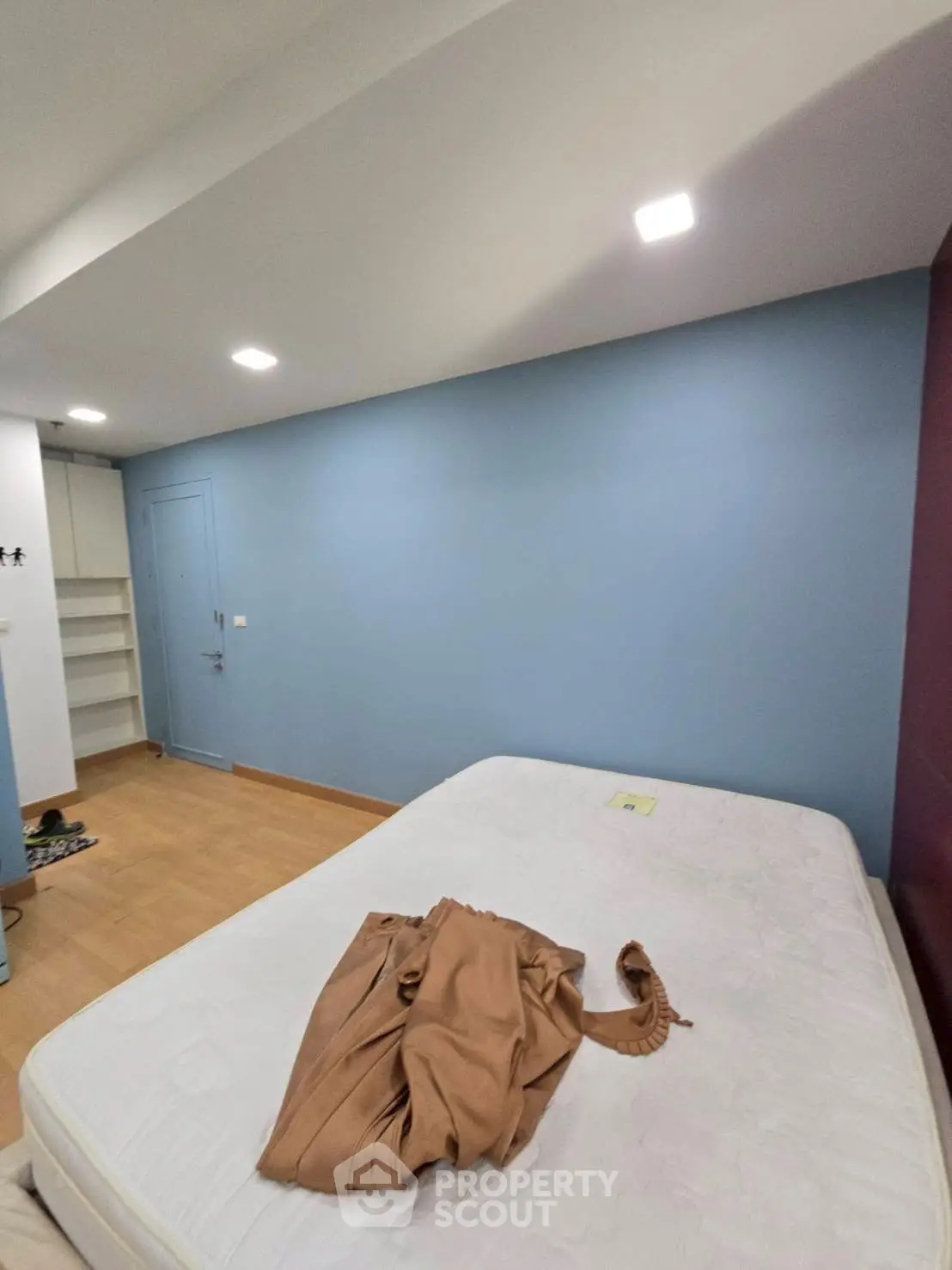 Spacious bedroom with blue accent wall and wooden flooring