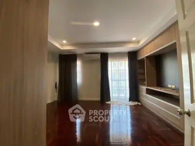 Spacious living room with wooden flooring and built-in shelves, perfect for modern living.