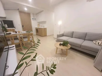 Modern living room with cozy gray sofa, wooden dining set, and minimalist decor in bright apartment.
