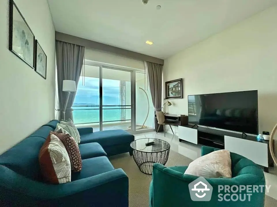 Luxurious living room with ocean view, modern furniture, and large TV in beachfront apartment.