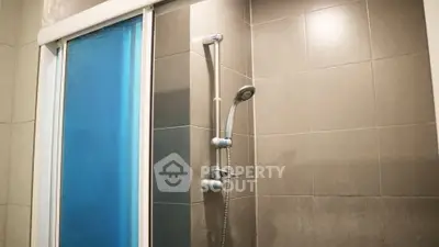 Modern bathroom shower with sleek tiles and sliding glass door.