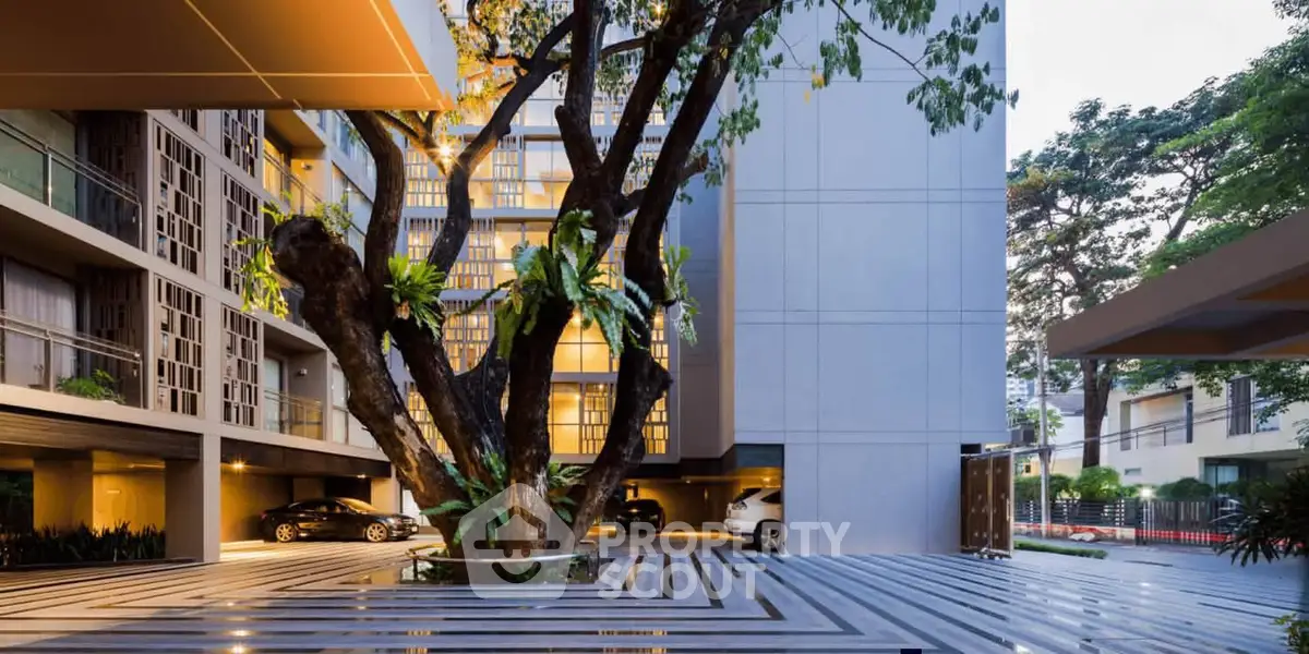 Modern building exterior with stylish parking area and lush greenery.