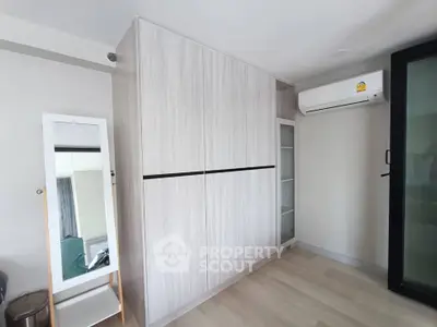 Modern bedroom with sleek wardrobe and air conditioning in a stylish apartment.