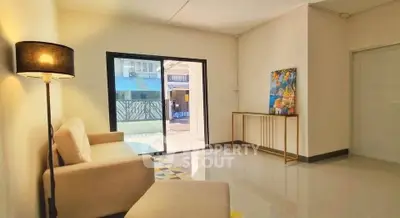 Bright living room with modern decor and large window overlooking outdoor area.