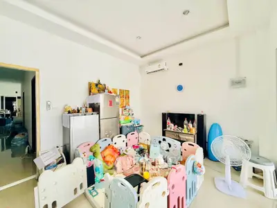 Spacious living room with modern decor and playful children's area, featuring air conditioning and ample natural light.