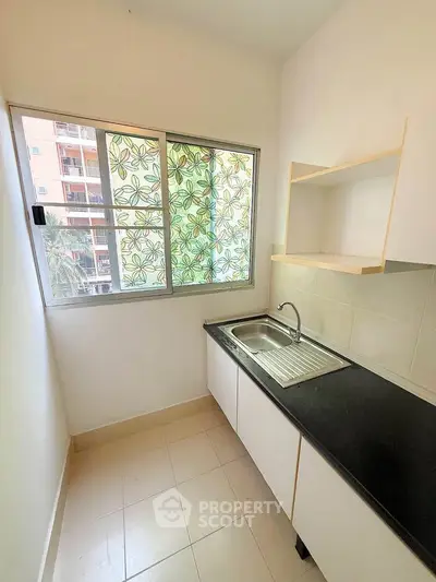 Compact kitchen with window and sleek countertop in modern apartment