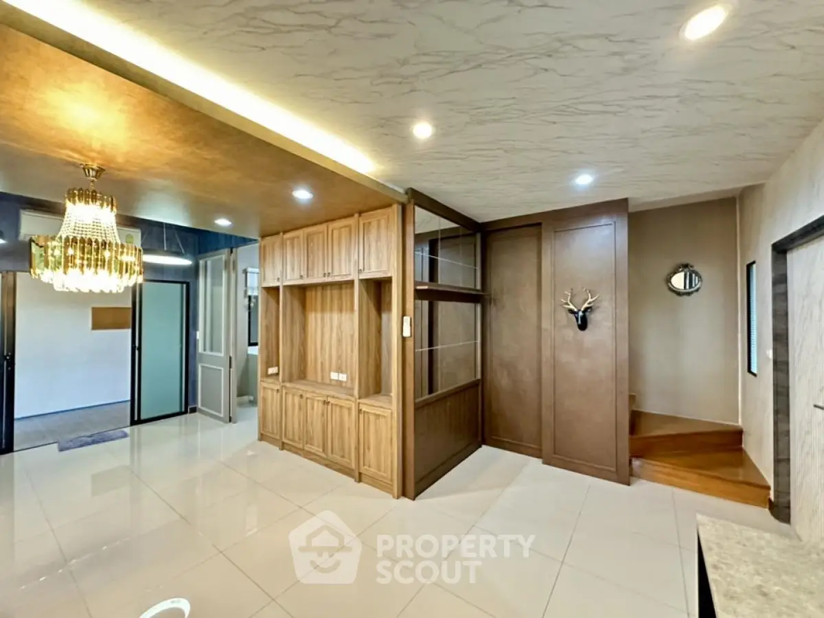 Spacious modern living area with elegant chandelier and wooden accents