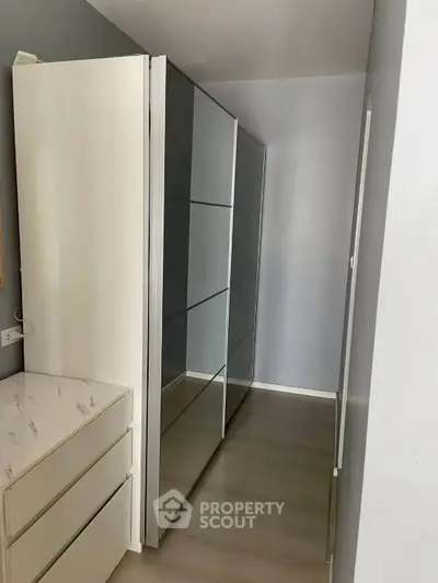 Modern walk-in closet with sleek mirrored wardrobe and minimalist design