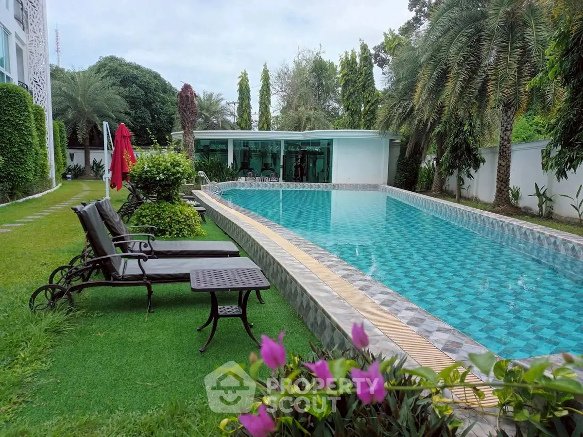Luxurious outdoor pool with lush garden and sun loungers, perfect for relaxation and leisure.