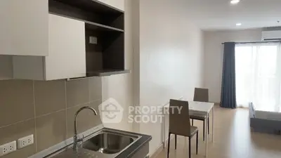 Modern studio apartment with open kitchen and dining area, featuring sleek design and natural light.