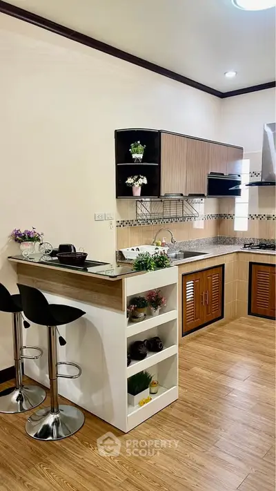 Modern kitchen with open layout and stylish bar stools, featuring wooden cabinets and sleek countertops.