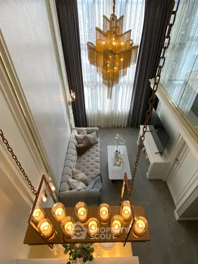 Luxurious living room with elegant chandelier and plush sofa in high-ceiling space.