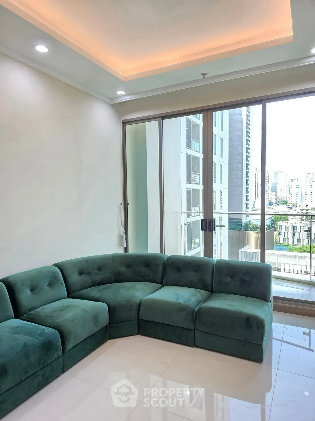 Modern living room with green sectional sofa and city view balcony