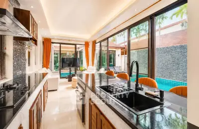 Luxurious open-plan kitchen and living area with pool view, featuring modern appliances and elegant decor.