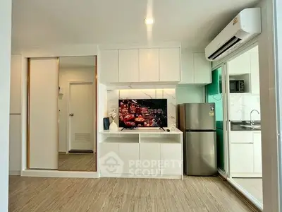 Modern living room with sleek design, featuring built-in TV unit and stainless steel fridge.