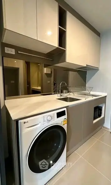 Modern kitchen with sleek cabinetry and built-in washing machine, perfect for urban living.