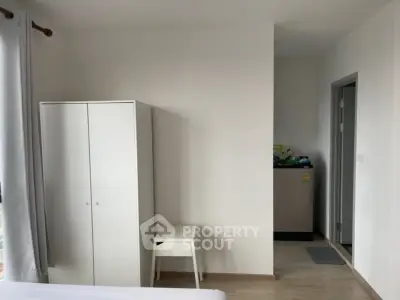 Modern minimalist bedroom with white wardrobe and washing machine corner.