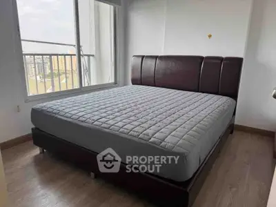 Spacious bedroom with large window and modern bed frame in a high-rise apartment.
