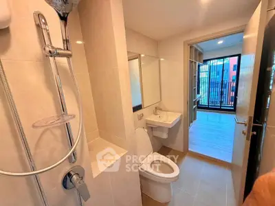 Modern bathroom with shower and toilet leading to a bright room with balcony view.