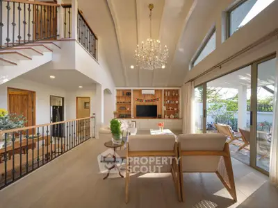 Spacious living room with elegant chandelier and large windows opening to a sunny patio.