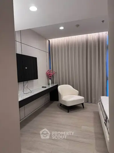 Modern living room with sleek TV setup and elegant armchair, perfect for relaxation.