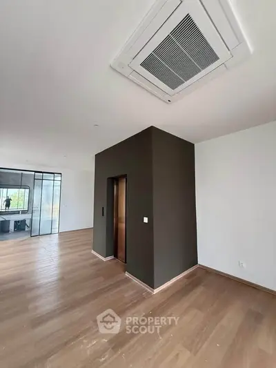 Spacious modern living room with sleek wooden flooring and stylish ceiling vent.