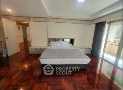 Spacious bedroom with hardwood floors and balcony access in modern apartment.