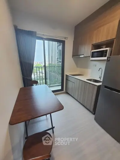 Modern kitchen with balcony view, featuring sleek cabinetry and stainless steel appliances.