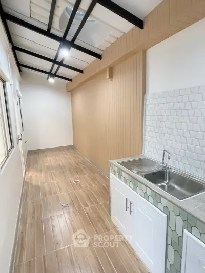 Modern narrow kitchen with sleek sink and stylish backsplash in a bright, airy space.