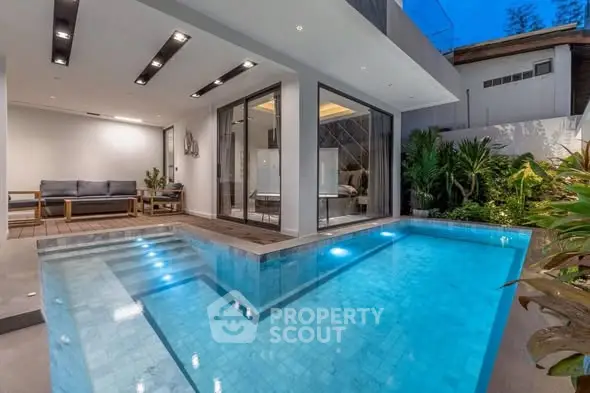 Luxurious modern home with private illuminated pool and stylish patio area.