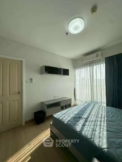 Bright and airy bedroom with modern furnishings and large window offering natural light.