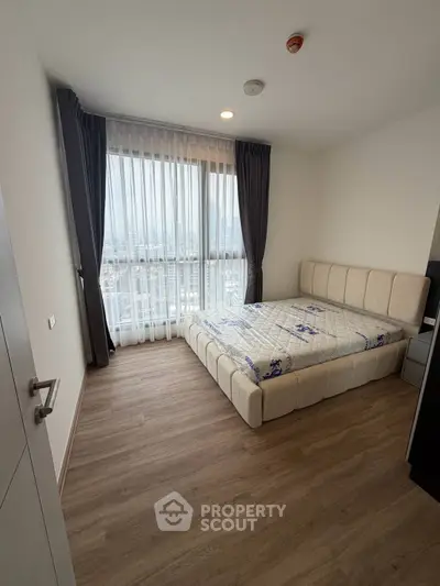 Modern bedroom with large window and stylish bed in a high-rise apartment.
