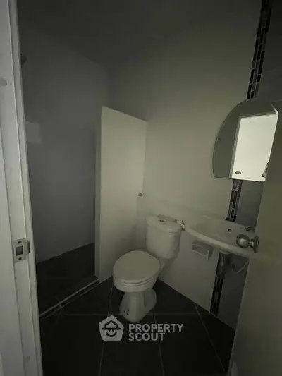 Compact bathroom with modern fixtures and dark tiled flooring.