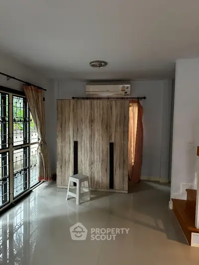 Spacious room with large window and air conditioning, featuring modern wardrobe and natural light.