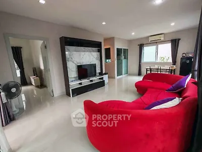Spacious living room with vibrant red sofa and modern entertainment center