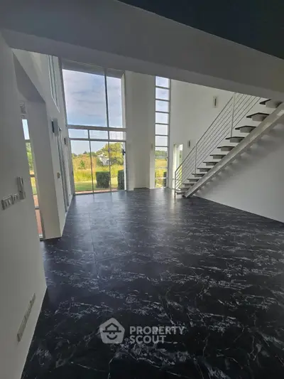 Spacious modern living room with high ceilings and large windows offering stunning views.