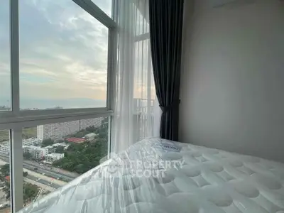 Stunning high-rise bedroom with panoramic city and sea views, featuring floor-to-ceiling windows and elegant decor.