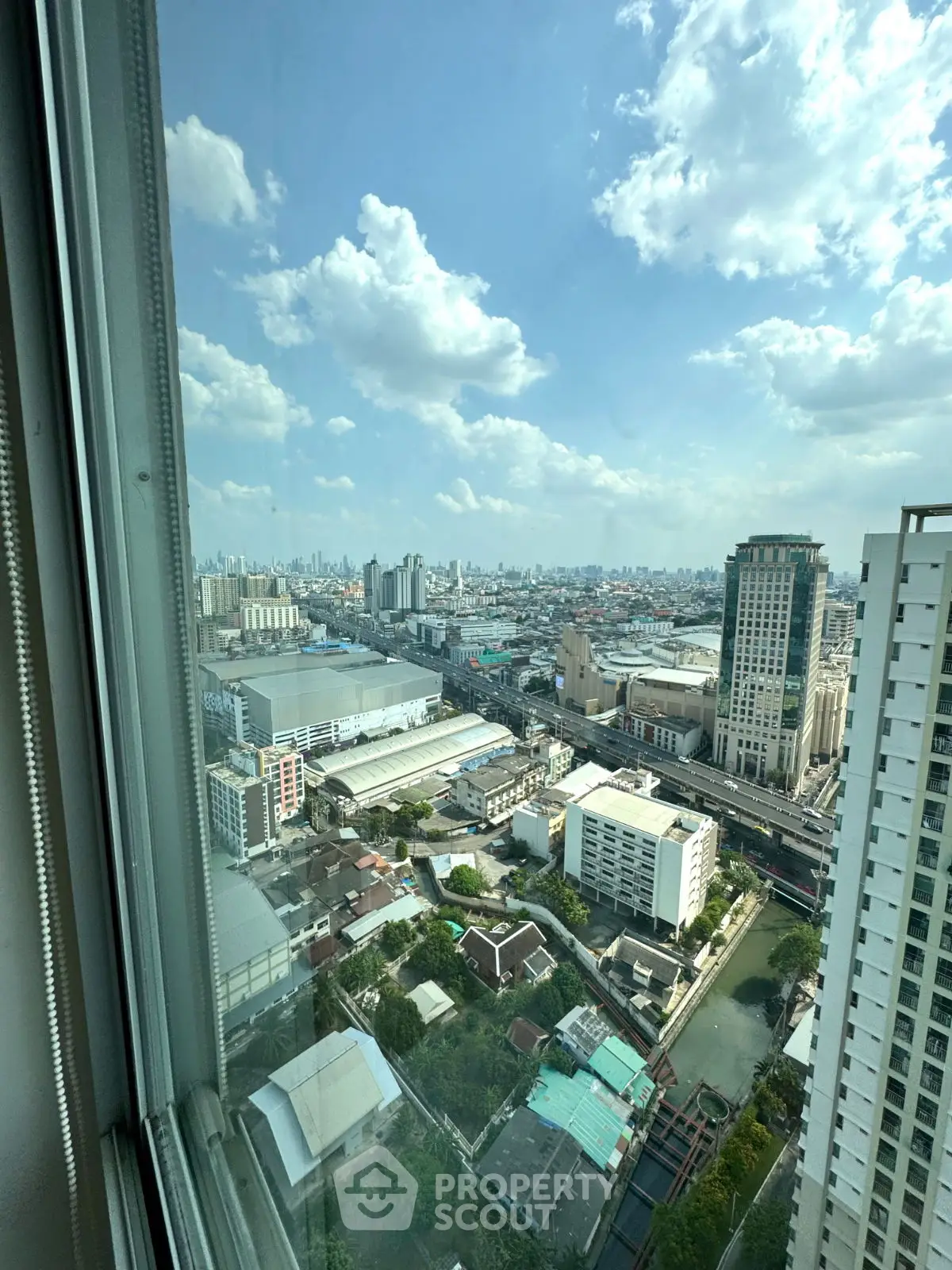 Stunning cityscape view from high-rise building window showcasing urban skyline and blue sky.